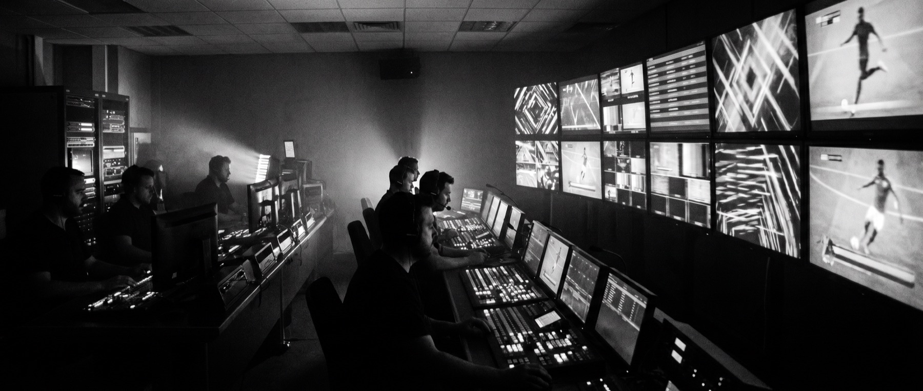 Sala de control de retransmisión deportiva con pantallas de datos, tratamiento en blanco y negro